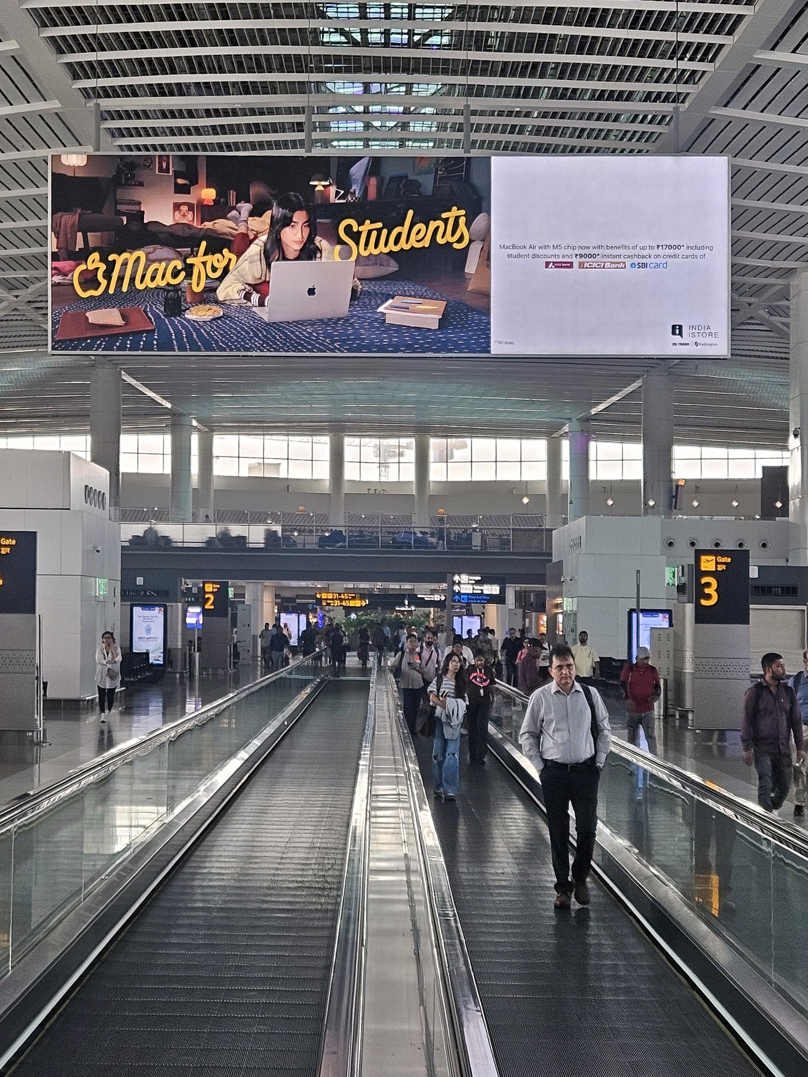 Mac for Students 2026 airport billboard above a terminal walkway