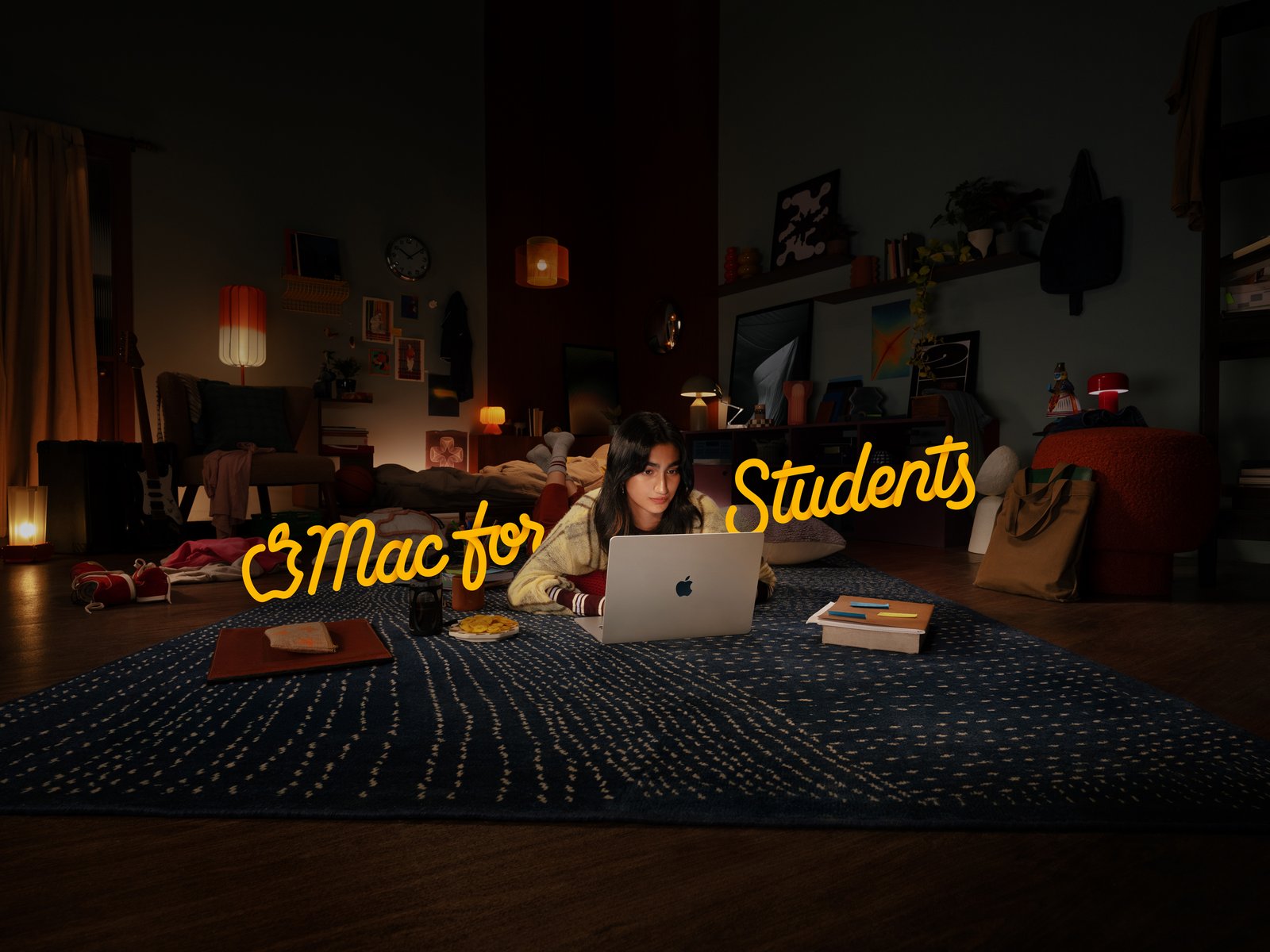 Mac for Students 2026 campaign master with yellow lettering framing a student using MacBook Air