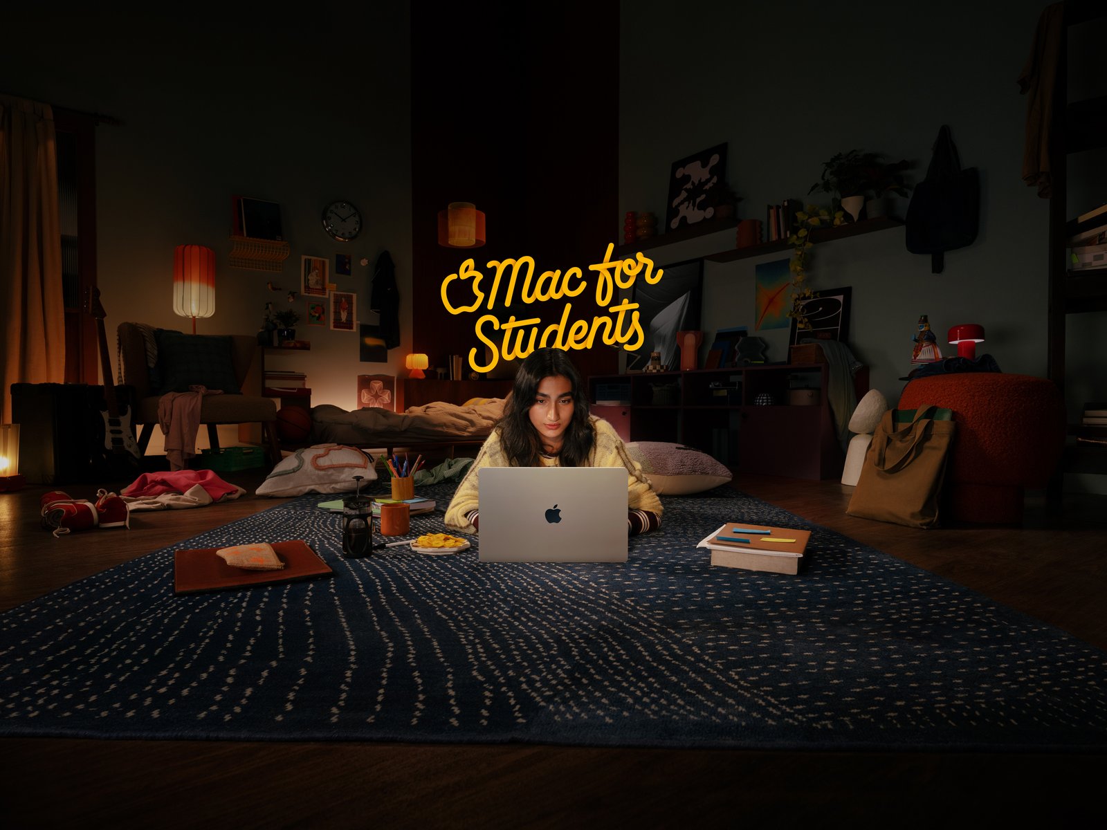 Mac for Students 2026 campaign master with stacked yellow lettering above a student using MacBook Air